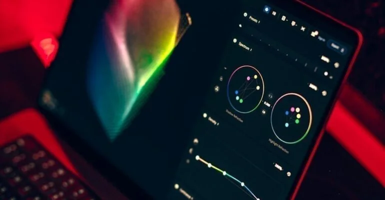 NYC video editor using color grading tools on a laptop screen.